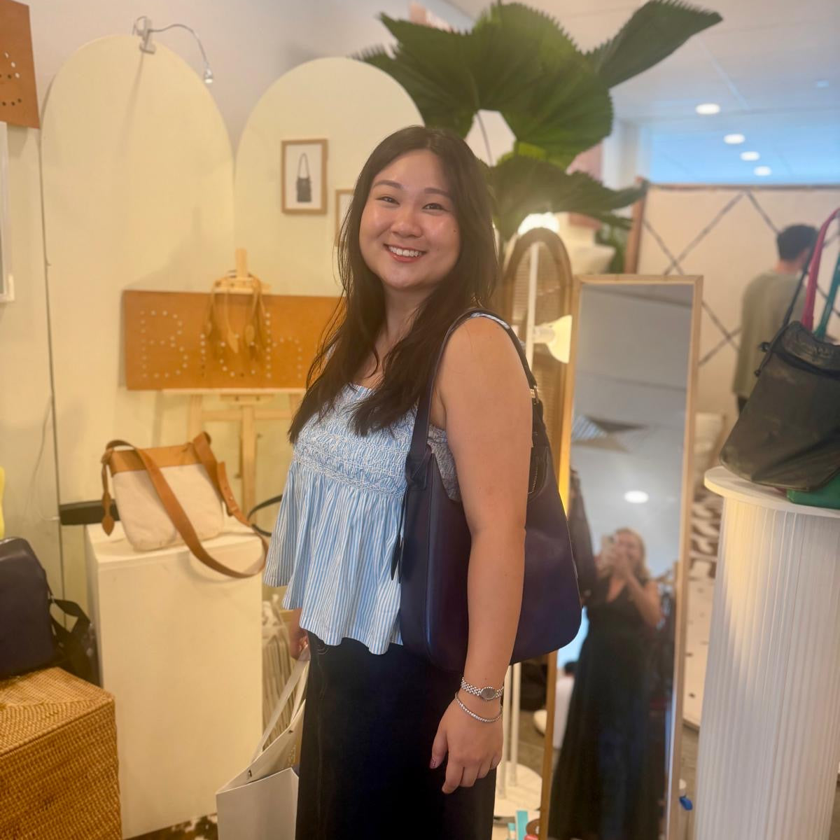 Woman standing in a store with a mirror and plant in the background