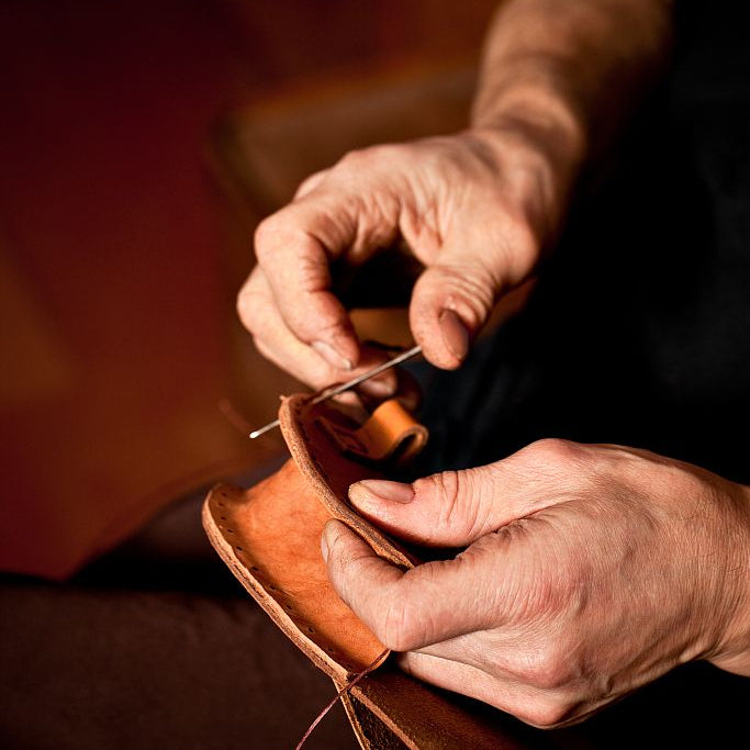 Person working with leather, possibly sewing or crafting, in a close-up shot. Image
