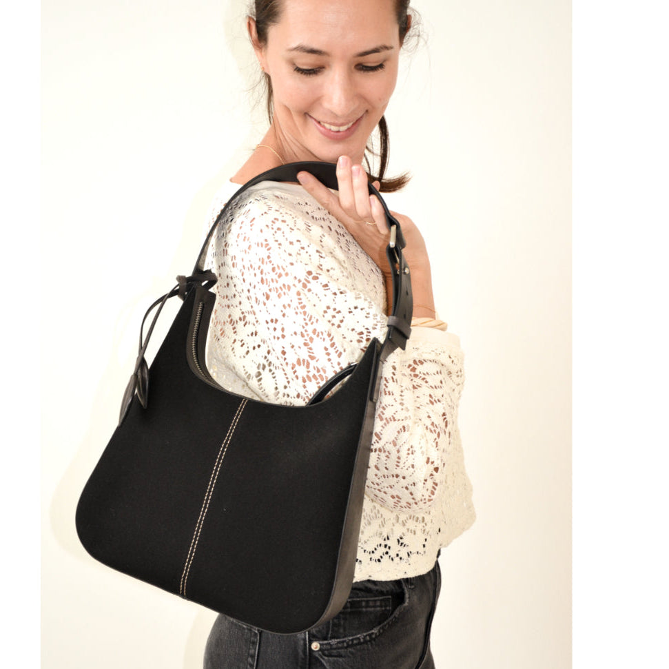 Woman holding a black handbag against a white background