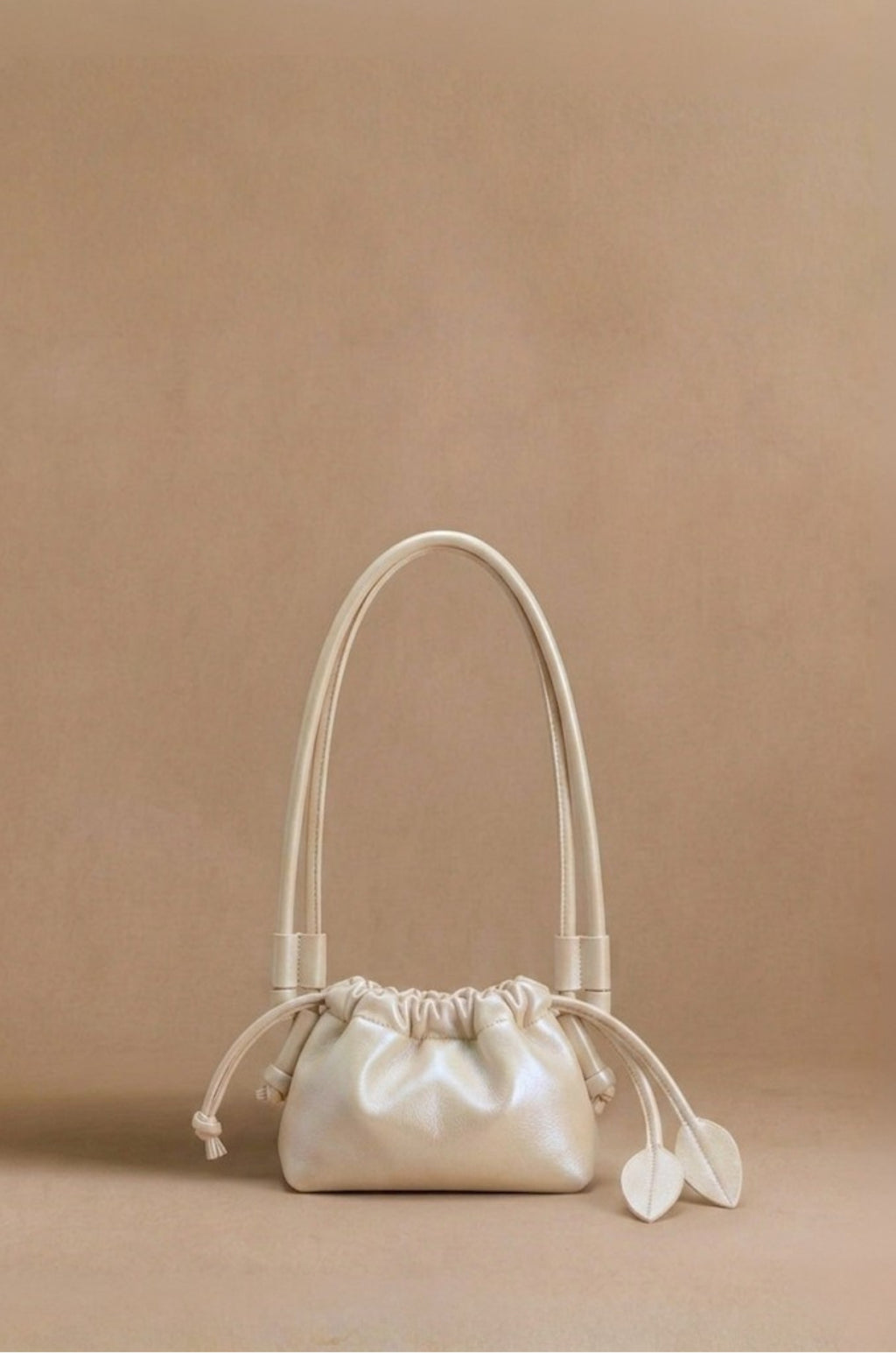 Eva Mini drawstring calf leather bag in champagne, front view — Biche Maison Dréan
