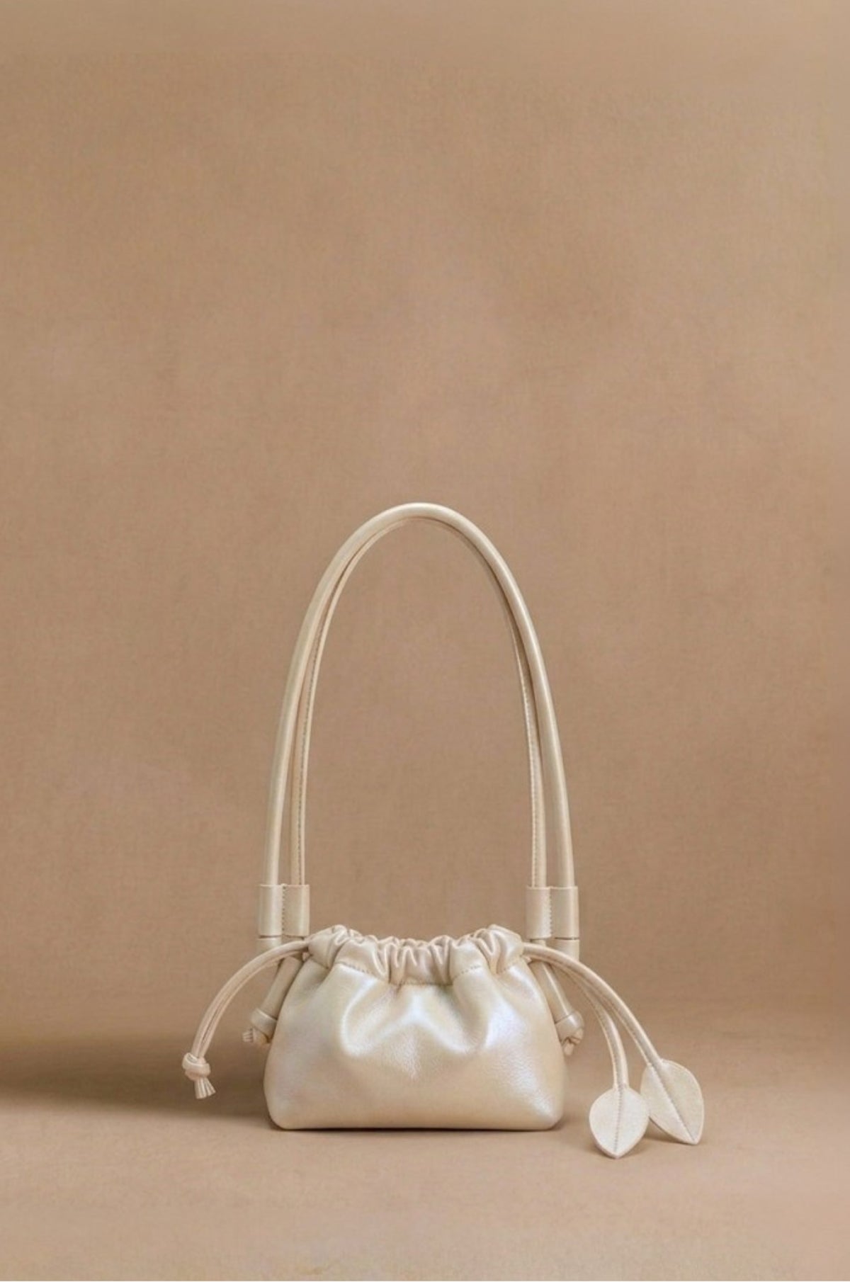 Eva Mini drawstring calf leather bag in champagne, front view — Biche Maison Dréan
